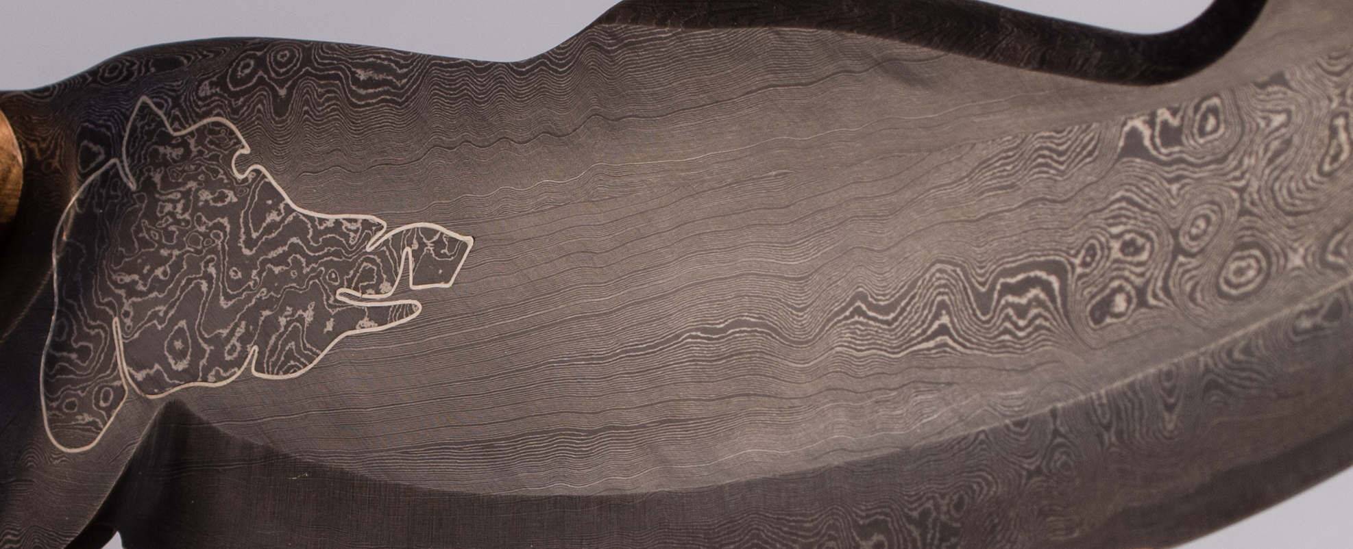 Close-up of a Damascus steel blade with the outline of a wild boar