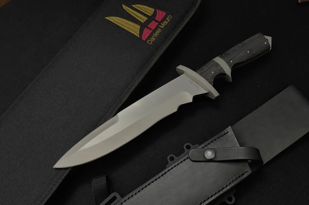 Replica of Jack Crain's knife for Demolition Man, polished spear-point blade and dark wooden handle with pins, beside the black leather sheath