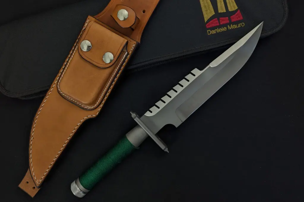 A reinterpretation of Jack Crain's LS-1: a larger blade with two different finishes and a green cord handle, beside the natural leather sheath