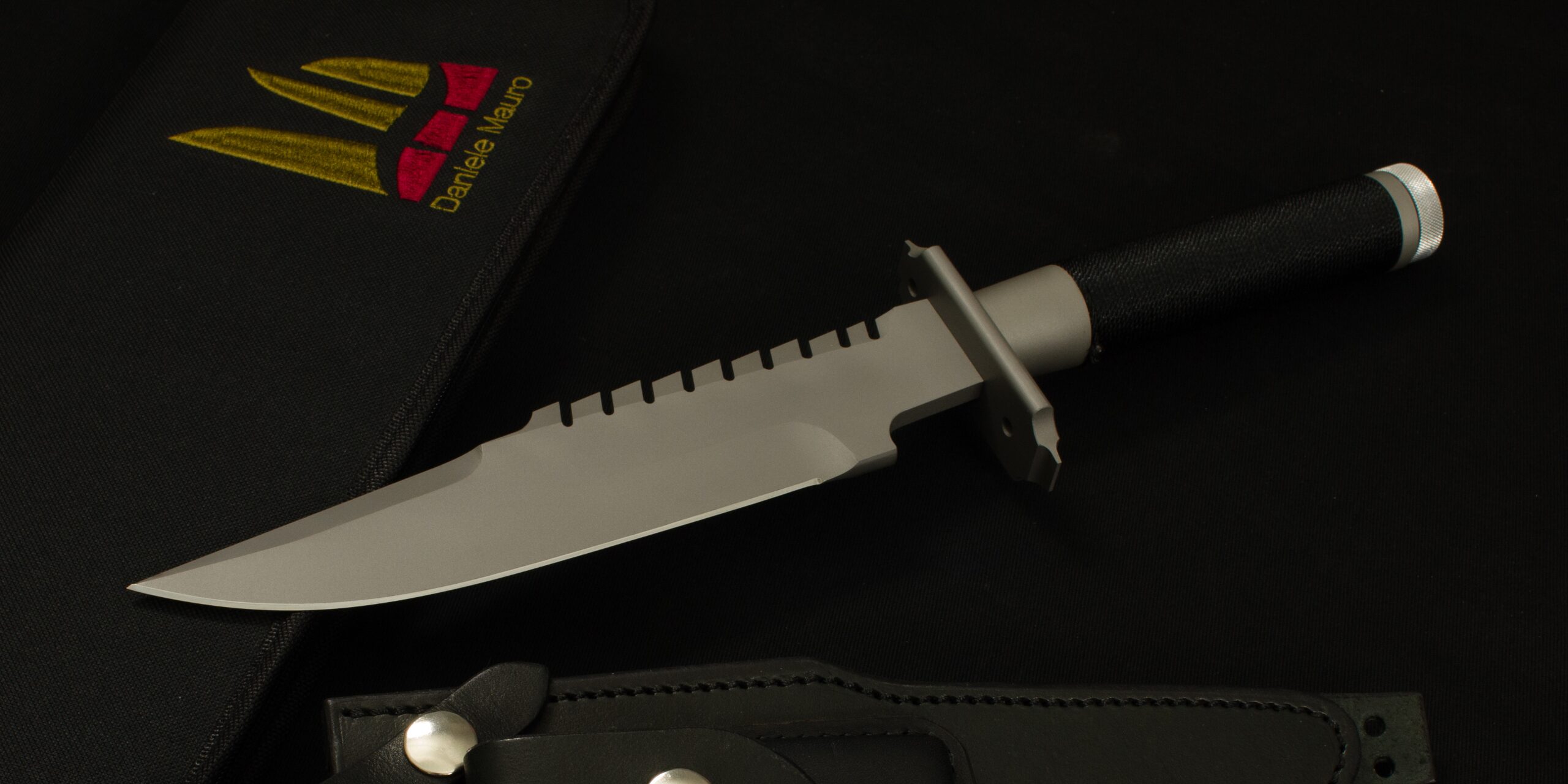 A replica of Jack Crain's LS-1 resting on its fabric case, blade with saw back and handle wrapped in black cord