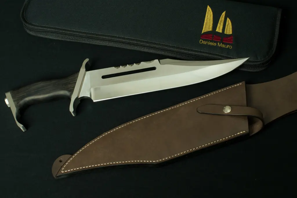 Replica of Gil Hibben's Rambo III, sawback blade and wooden handle, beside the brown leather sheath