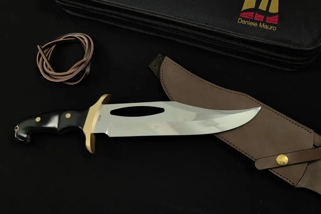 Replica of Jimmy Lile's prototype for Rambo III from the right, black handle and brass guard, beside the leather sheath